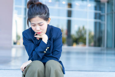 Mid adult woman looking away while sitting outdoors