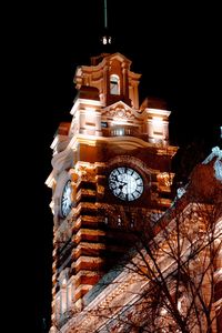 Low angle view of clock tower at night