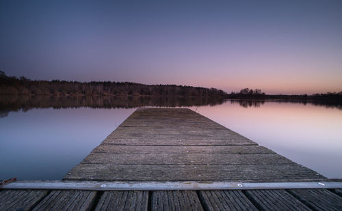 Pier over lake against sky during sunset