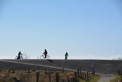 Low angle view of people riding bicycle on hill against sky