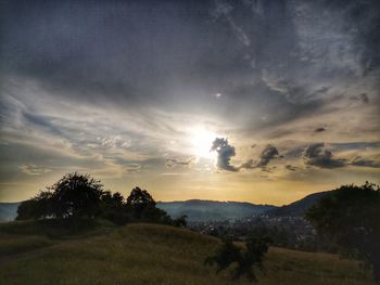 Silhouette trees on landscape against sky during sunset