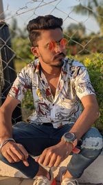 Young man wearing sunglasses sitting outdoors