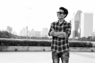 Young man wearing sunglasses standing against city