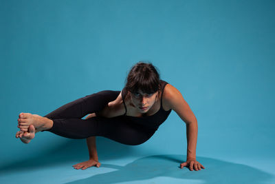 Young woman exercising against blue background