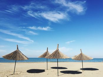 Scenic view of beach and parsols against blue sky