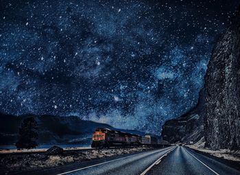 Road amidst trees against sky at night