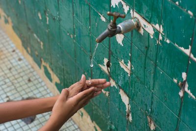 Cropped image of person washing hands in running water outdoors