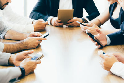 Midsection of woman using mobile phone on table