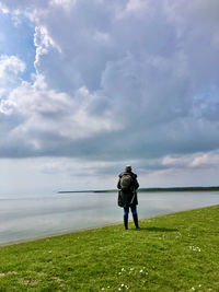 Rear view of man standing on field against sky