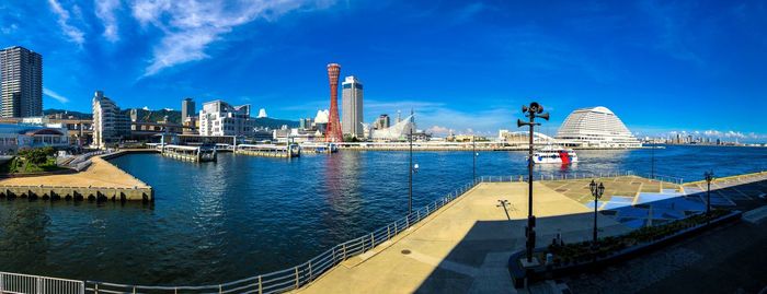 City by river and buildings against sky