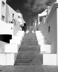 Rear view of woman on staircase amidst buildings in city