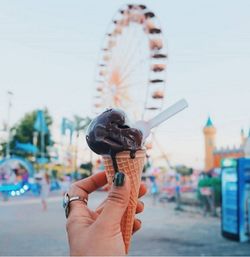 Close-up of hand holding carousel against sky
