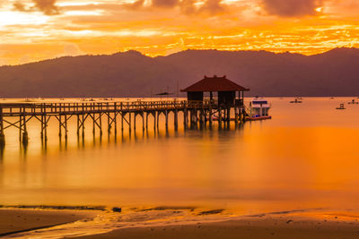 A wooden pier stretches out into a calm bay at sunset, near trenggalek, east java, indonesia.