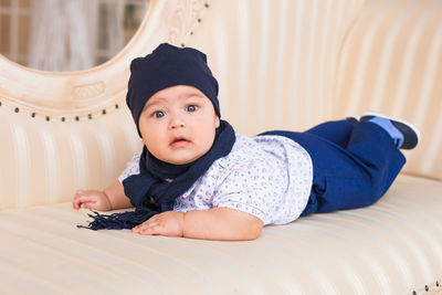 Portrait of cute boy sitting on bed at home