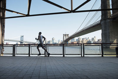 Side view of man jogging on floor against clear sky