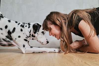 Side view of woman with dog on floor at home