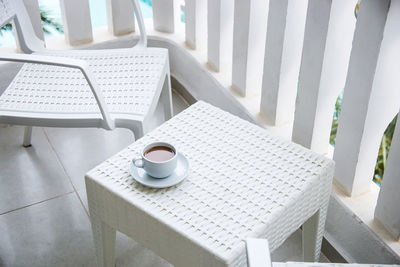 A cup of coffee with milk in a white bowl on the light balcony of the hotel 