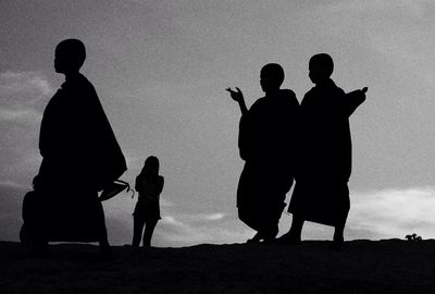 Silhouette friends standing against sky