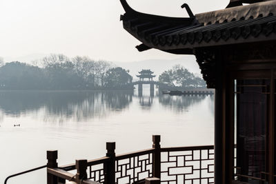 Traditional buildings by lake in foggy weather