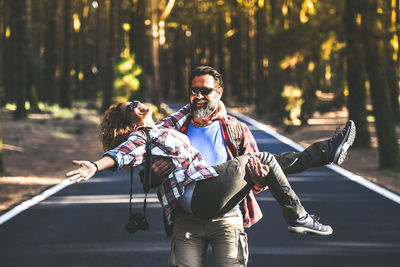 Rear view of man and woman on road in forest