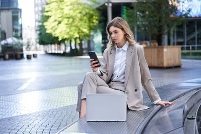 Young woman using phone while sitting on table