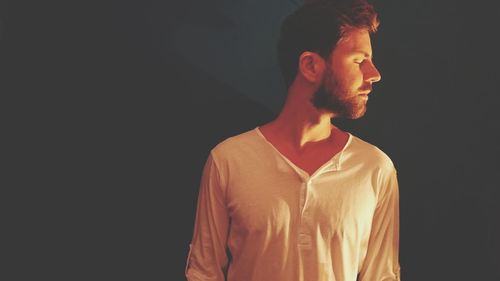 Young man with eyes closed standing against wall