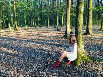 Woman sitting on tree trunk in forest