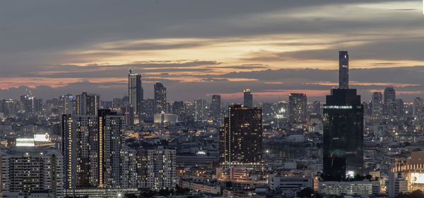 Modern buildings in city against sky during sunset