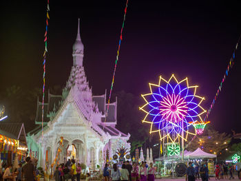 Group of people in amusement park at night