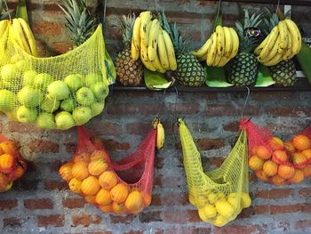 Fruits hanging in nets on wall at market for sale