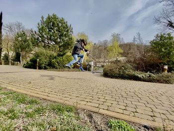 Man riding bicycle on footpath against sky