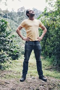 Full length portrait of young man standing against plants