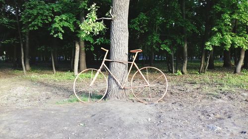 Bicycle parked by tree on field