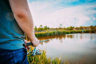 Midsection of man holding plants at lake