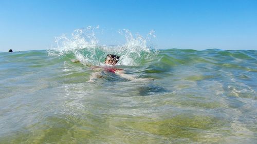 Boy splashing water while swimming in sea