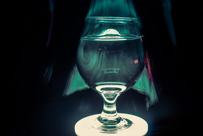 Close-up of wine glass on table against black background