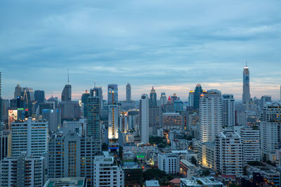 Aerial view of buildings in city against cloudy sky