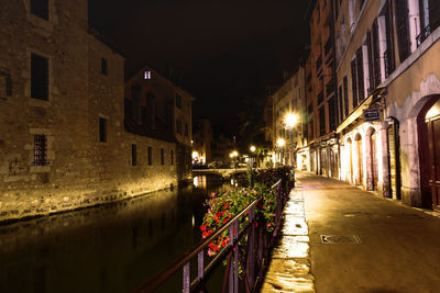 Illuminated street amidst buildings in city at night