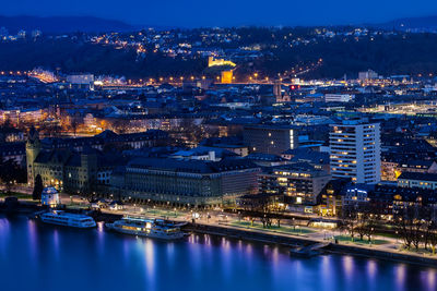 Illuminated buildings by river at night