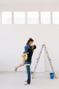 A young couple in love have moved into a new house and are making repairs painting white walls