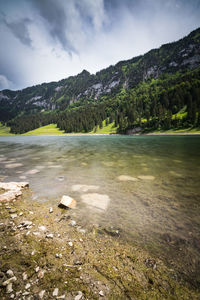 Scenic view of lake by mountains against sky