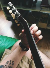 Cropped hand of man playing guitar at home