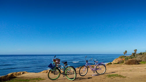 Bicycles on beach against clear blue sky