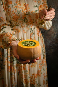 Woman holding healthy pumpkin cream soup and spoon