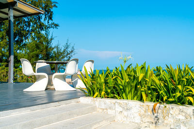 Chairs by swimming pool against blue sky on sunny day