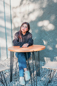 Portrait of young woman sitting on chair in winter