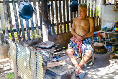 Portrait of shirtless man standing by tree