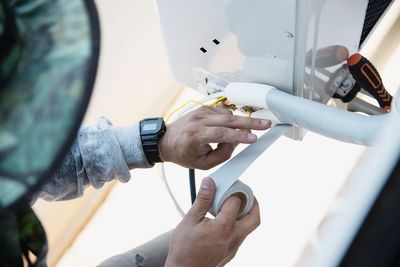 Man is installing wall compressor of air conditioner during hot season