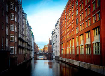 Canal amidst buildings against sky in city