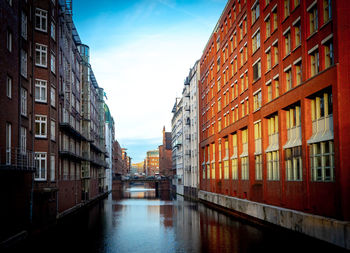 Canal amidst buildings against sky in city